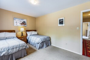 A hotel room with two beds, a nightstand with a lamp, and two framed pictures on the wall.