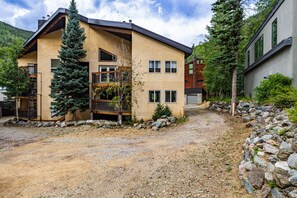 A multi-story building with a sloped roof, a balcony, and a gravel driveway.