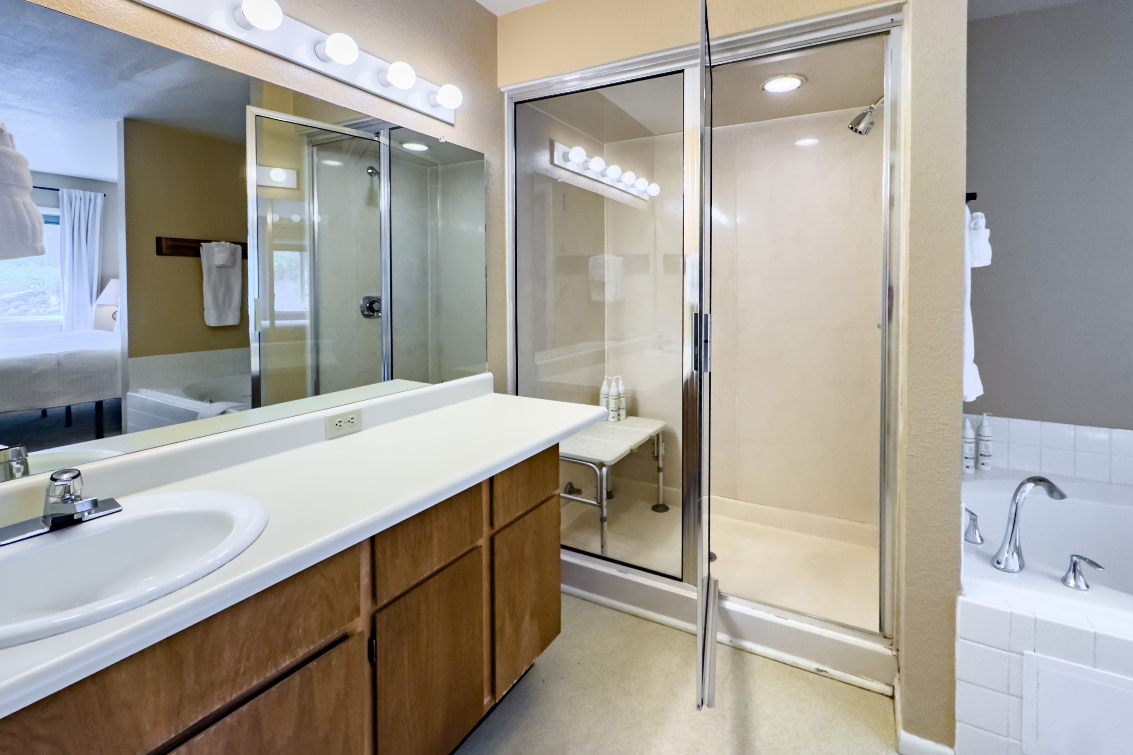 Une salle de bain moderne avec une douche à parois de verre, un grand miroir et un meuble-lavabo.