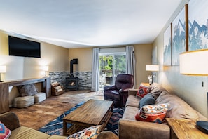 A cozy living room with a fireplace, comfortable seating, and a television mounted on the wall.
