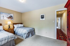 A hotel room with two beds, a nightstand with a lamp, a painting on the wall, and a red carpet leading to the door. - Lake Fork - Ski-In / Ski-Out, Gas Stove, Parking (Taos Ski Valley)