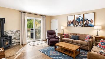 A living room with a fireplace, leather armchair, sofa, and a rug.