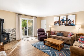 A living room with a fireplace, leather armchair, sofa, and a rug.
