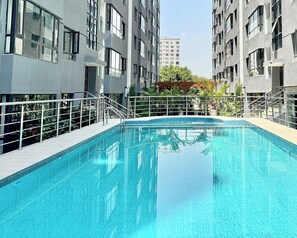 A swimming pool surrounded by modern buildings with balconies, a clear sky, and some greenery. - A calm, stylish escape 
Perfect for productive workdays or relaxing getaways. (Nairobi)