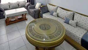 A living room with a sofa, a coffee table, and a dining table. - RESIDANCE F5 FRANGE MARITIME An AKID LOTFI (Bir El Djir)