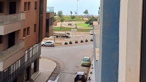 A multi-story building with balconies, a street with parked cars, and a playground in the background. - RESIDANCE F5 FRANGE MARITIME An AKID LOTFI (Bir El Djir)