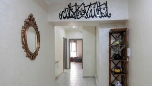 A hallway with a decorative mirror, a shelf with decorative items, and a sign with Arabic calligraphy. - RESIDANCE F5 FRANGE MARITIME An AKID LOTFI (Bir El Djir)