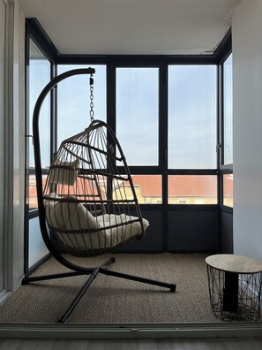 Ein Zimmer mit Hängekorbschaukel, großem Fenster, Teppichboden und rundem Tisch.