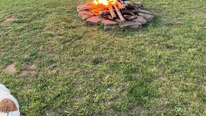 A house with a stone foundation, a wooden deck, and a fire pit in the yard.