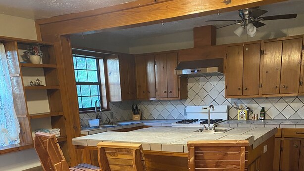 A kitchen with wooden bar stools, a central island, and wooden cabinets.