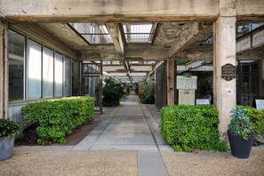 A covered walkway with concrete pillars, glass doors, and potted plants. - Cozy + Quiet, Moon Studio on the Atlanta Beltline. Everything you want. (Atlanta)