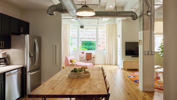 A modern kitchen with stainless steel appliances, a wooden dining table with fruit, and a view to a brick wall. - Cozy + Quiet, Moon Studio on the Atlanta Beltline. Everything you want. (Atlanta)