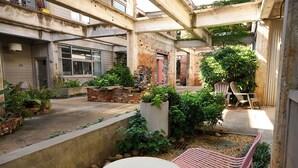 An outdoor courtyard with a white table, a pink chair, and various plants. - Cozy + Quiet, Moon Studio on the Atlanta Beltline. Everything you want. (Atlanta)