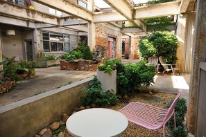 An outdoor courtyard with a white table, a pink chair, and various plants. - Cozy + Quiet, Moon Studio on the Atlanta Beltline. Everything you want. (Atlanta)