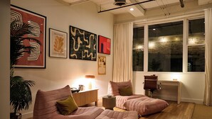 A modern living room with two pink sofas, a coffee table, and a side table. There are abstract art pieces on the wall, a large window with curtains, and a potted plant. - Cozy + Quiet, Moon Studio on the Atlanta Beltline. Everything you want. (Atlanta)