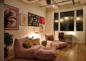 A modern living room with two pink sofas, a coffee table, and a side table. There are abstract art pieces on the wall, a large window with curtains, and a potted plant. - Cozy + Quiet, Moon Studio on the Atlanta Beltline. Everything you want. (Atlanta)