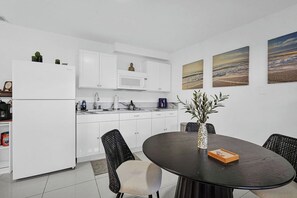 A modern kitchen with white cabinets, a black dining table, and a vase with greenery. - PRIVATE TROPICAL RETREAT  JACUZZI, TIKI HUT & OUTDOOR PARADISE (Homestead)