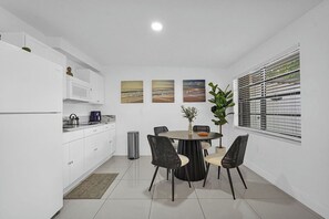 A modern kitchen with white cabinets, a dining table with four chairs, and a window with blinds. - PRIVATE TROPICAL RETREAT  JACUZZI, TIKI HUT & OUTDOOR PARADISE (Homestead)