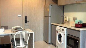 A compact kitchen with a washing machine, a microwave, and a refrigerator. - Luxurious 1-bedroom Apartment Near BTS Thonglor, Bangkok (Bangkok)