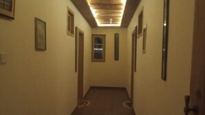 A narrow hallway with framed pictures on the walls, a wooden floor, and a ceiling with a light fixture.