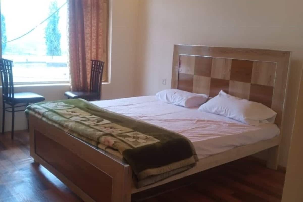 Un dormitorio con una cama de madera, una silla y una ventana con cortinas.