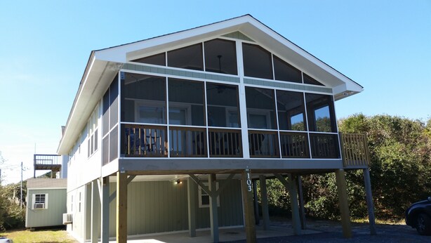 Een tweelaags huis met een balkon, een overdekte veranda en een kleine aanleunschuur.