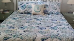 Een slaapkamer met een bed, twee nachtkastjes, een wandlamp en een schilderij aan de muur.