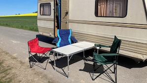 Un véhicule récréatif équipé d’une table et de trois chaises à l’extérieur.