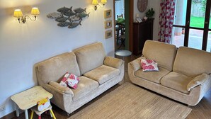 A living room with two sofas, a small table, a mirror, wall-mounted lights, and a view through a door. - In quiet and relaxing setting 1.5km from the sea, suitable for families and friends, (Anzio)