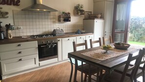 A kitchen with white cabinets, a wooden countertop, a stove, and a dining table with chairs. - In quiet and relaxing setting 1.5km from the sea, suitable for families and friends, (Anzio)