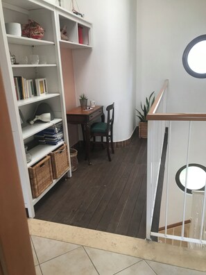 A room with a wooden floor, a white bookshelf, a small table with a chair, and a potted plant. - In quiet and relaxing setting 1.5km from the sea, suitable for families and friends, (Anzio)