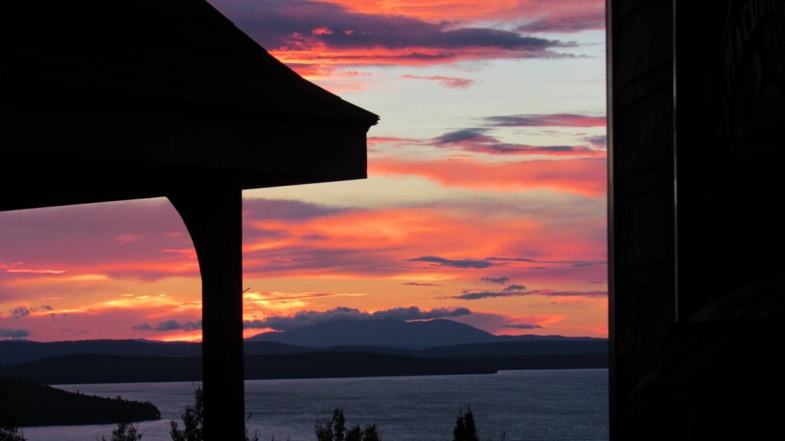 A sunset view with a silhouette of a building and a body of water.