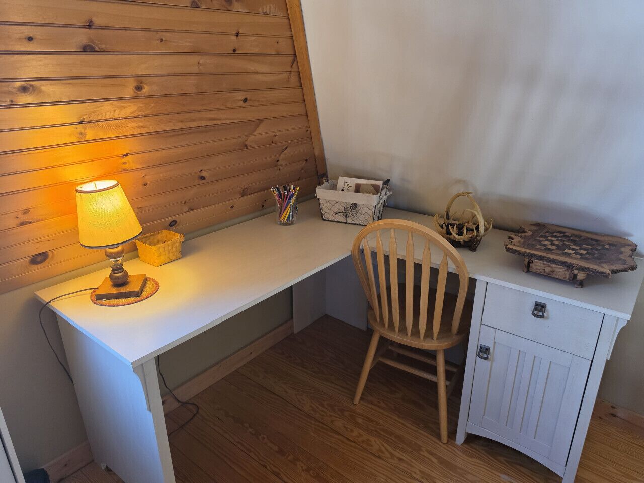 Ein Holztisch mit Lampe, einem Stuhl, einer kleinen Aufbewahrungsbox und einem Schachbrett.