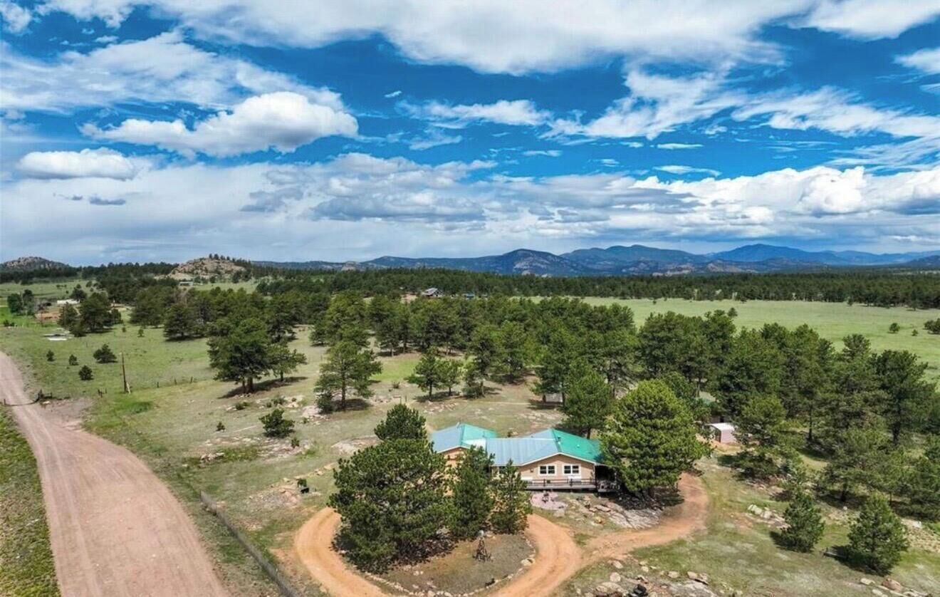 A rural property with a house surrounded by trees and open fields.