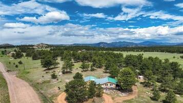 A rural property with a house surrounded by trees and open fields.