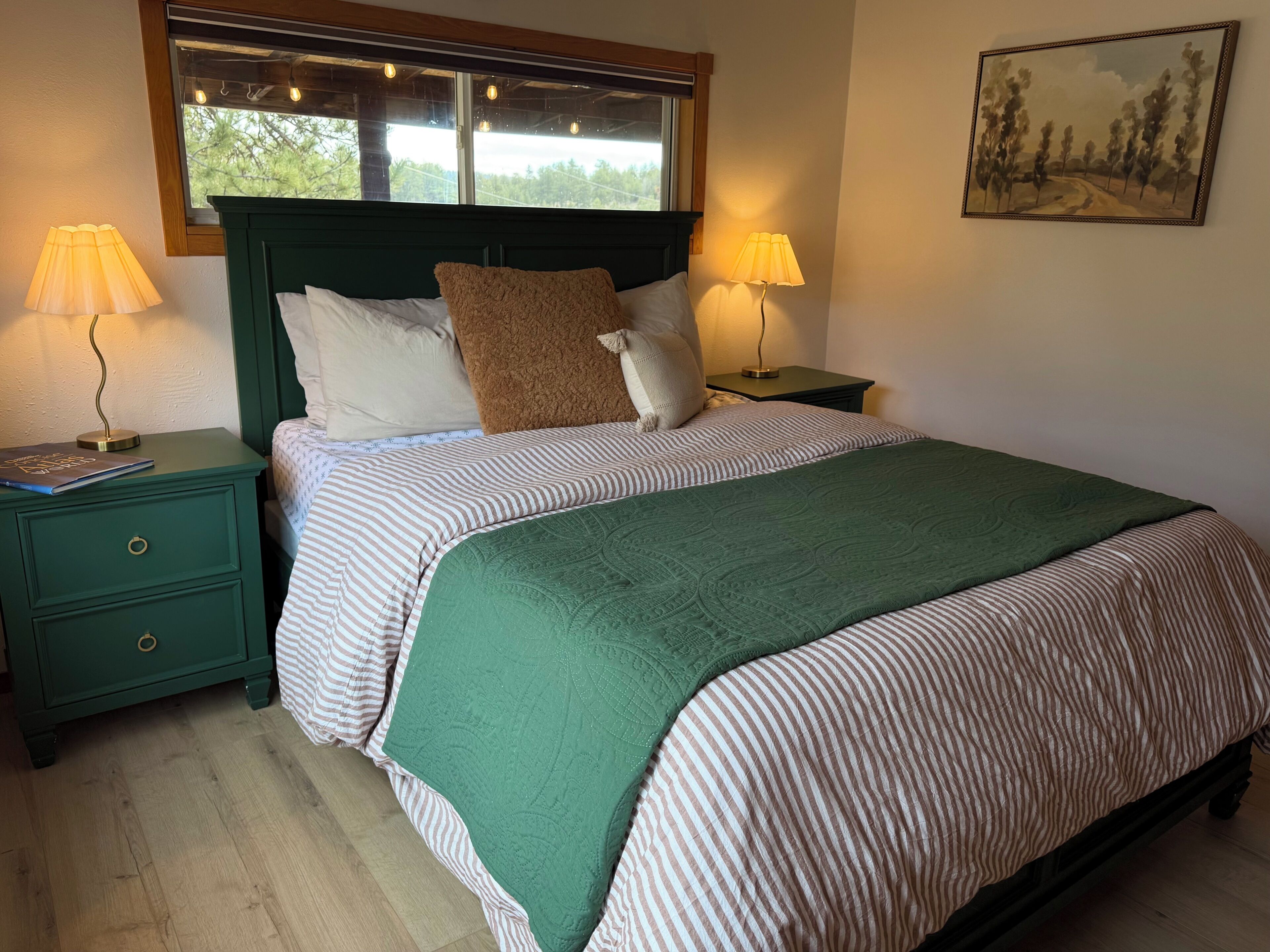 A bed with striped bedding, a green throw, and two bedside lamps.