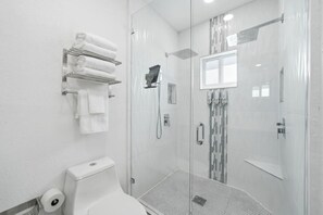Une salle de bain moderne avec une douche à parois de verre, des toilettes et un porte-serviettes.