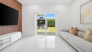Ein modernes Wohnzimmer mit Flachbildfernseher, einer Couch und einer Schiebetür zu einer Außenpatio.