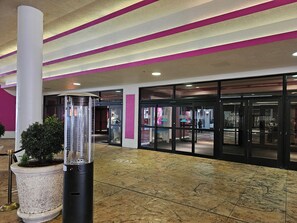 Un hall d’hôtel avec un sol carrelé, une plante en pot, une colonne et une entrée avec une porte en verre.