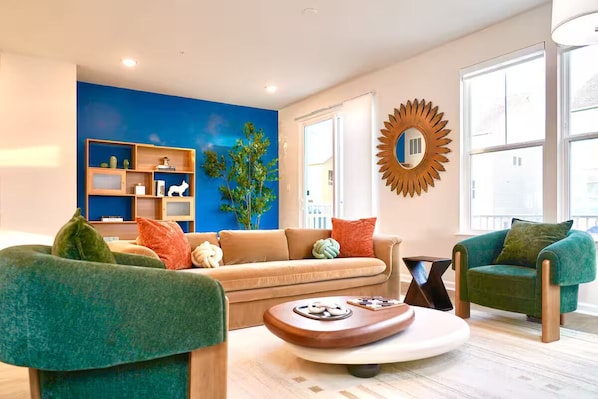 Un salon moderne avec un mur d’accent bleu, une bibliothèque en bois, un canapé, deux fauteuils et une table basse.