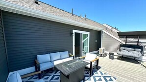 A covered outdoor deck with a sofa, chairs, a table, and a swing. - Brand-New- Rooftop Luxe 4BR/5BA, 15 Min to DC+ MGM (Upper Marlboro)