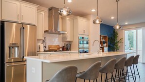 A modern kitchen with stainless steel appliances, a large island with bar stools, and pendant lighting. - Brand-New- Rooftop Luxe 4BR/5BA, 15 Min to DC+ MGM (Upper Marlboro)