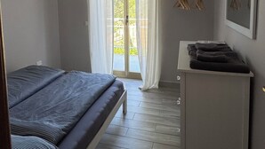 Une chambre à coucher comprenant un lit, un bureau, une chaise, une fenêtre avec des rideaux et un appareil de climatisation.