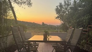 Une terrasse avec une table et quatre chaises, entourée de verdure et offrant une vue sur le paysage.
