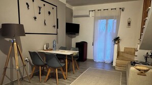 Un salon comprenant une table à manger, des chaises, une lampe, un téléviseur, un escalier et un tapis à motifs.