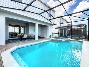 A swimming pool with a glass enclosure, outdoor seating, and a view of the sky. - Dream Home 7BR – Pool, Hot Tub, Game Room & Theater - Near Disney! (Davenport)
