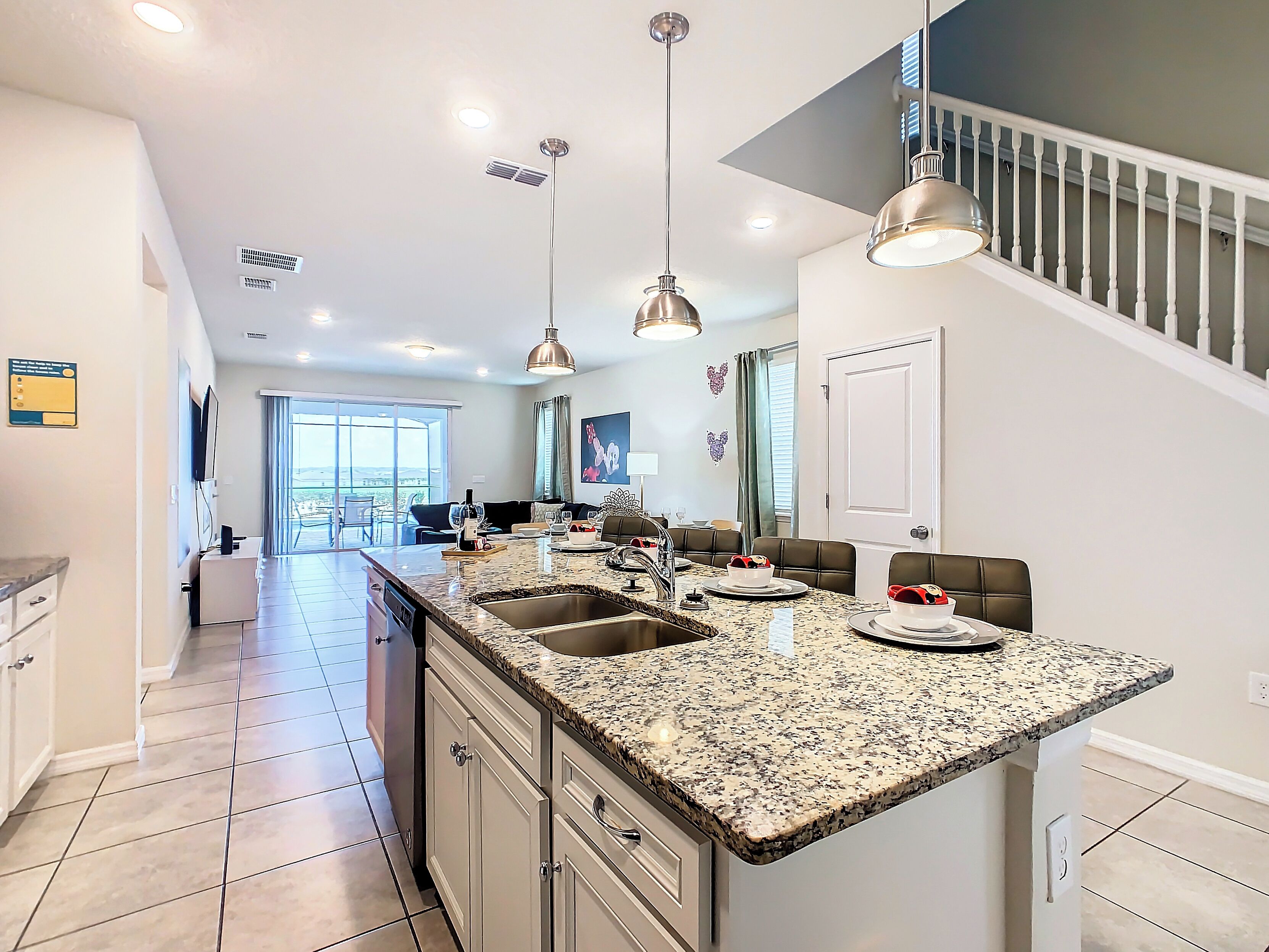 A modern kitchen with a large island, stainless steel appliances, and pendant lighting.