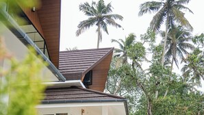 A modern house with a sloped roof, a covered porch, and a paved driveway. - River Suite with River View (Kochi)