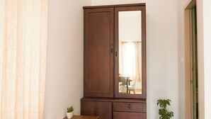 A room with a wooden cabinet, a small table, a potted plant, and a black mat. - River Suite with River View (Kochi)