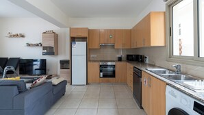 Een moderne keuken met houten kastjes, een ingebouwde oven, een vaatwasser en een groot raam.